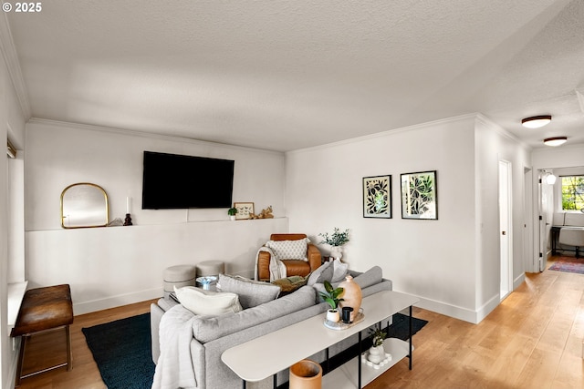 living room featuring light wood-style flooring, a textured ceiling, crown molding, and baseboards