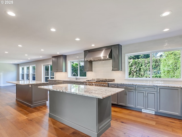 kitchen featuring gray cabinetry, wall chimney exhaust hood, and a kitchen island