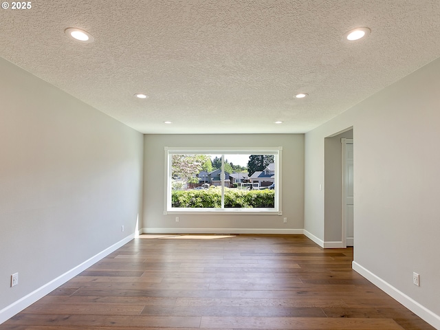 unfurnished room featuring baseboards, dark wood finished floors, recessed lighting, and a textured ceiling
