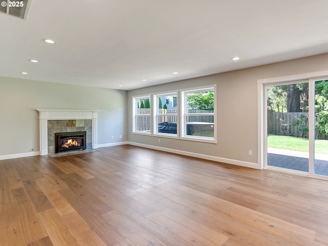 unfurnished living room with a tile fireplace, wood finished floors, baseboards, and recessed lighting