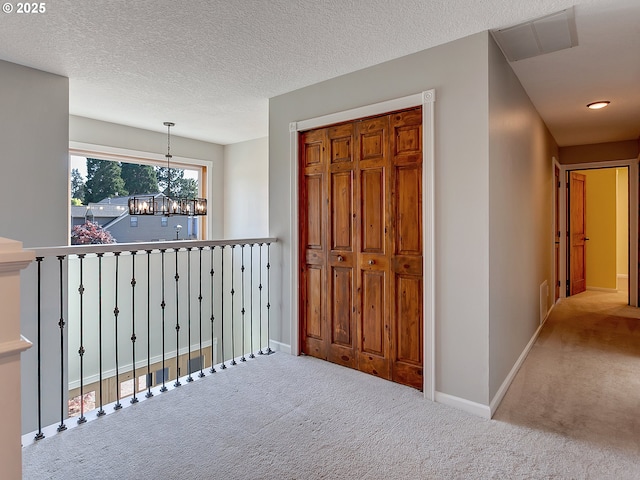hall with carpet flooring, visible vents, baseboards, and a notable chandelier