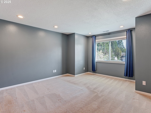 spare room with carpet, a textured ceiling, and baseboards