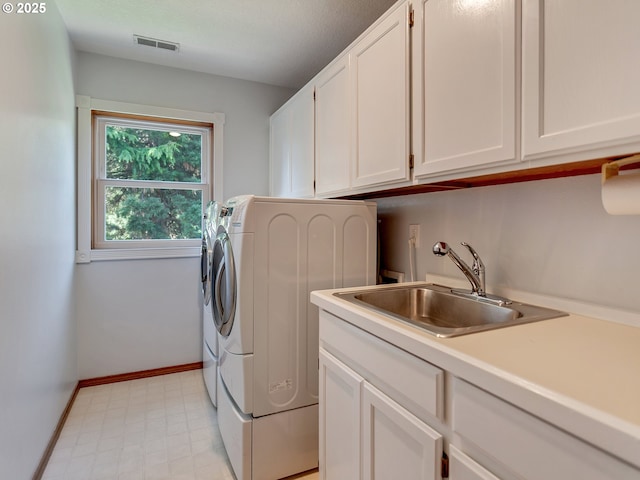 washroom featuring washing machine and dryer, a sink, cabinet space, visible vents, and baseboards