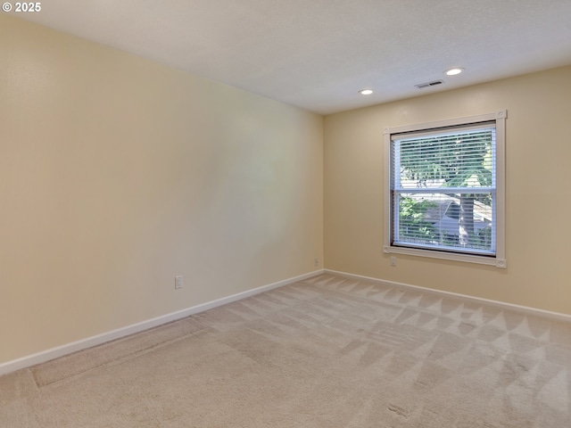 spare room featuring light colored carpet, baseboards, visible vents, and recessed lighting