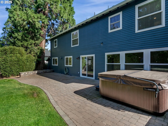 back of house with a yard, a hot tub, and a patio