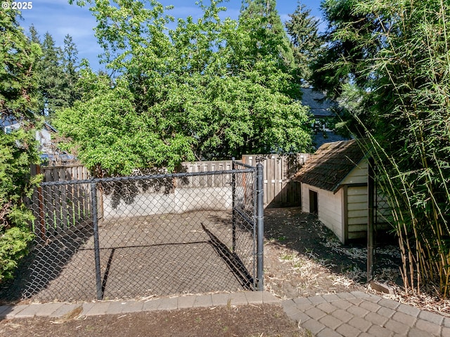view of gate featuring a fenced backyard, a storage shed, and an outdoor structure