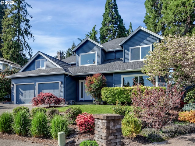 craftsman-style home with a front yard, a garage, a shingled roof, and driveway