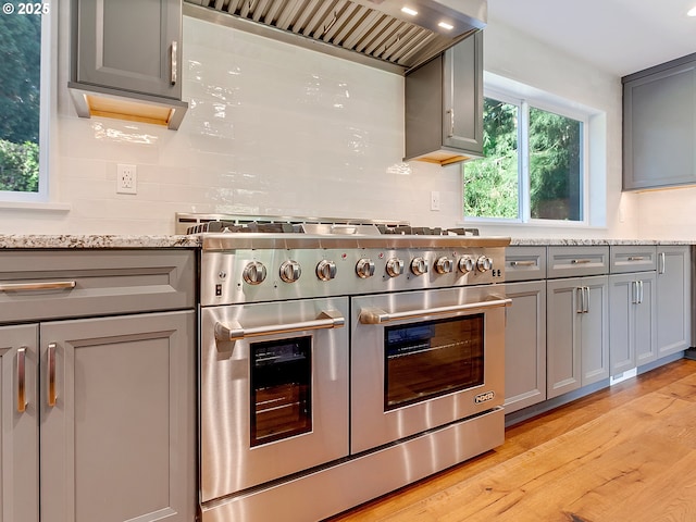 kitchen with double oven range, custom range hood, decorative backsplash, and gray cabinets