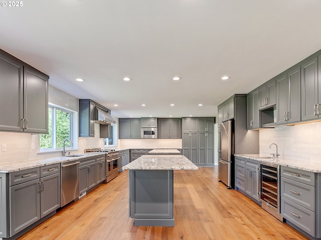 kitchen with wine cooler, light stone counters, a sink, and high quality appliances