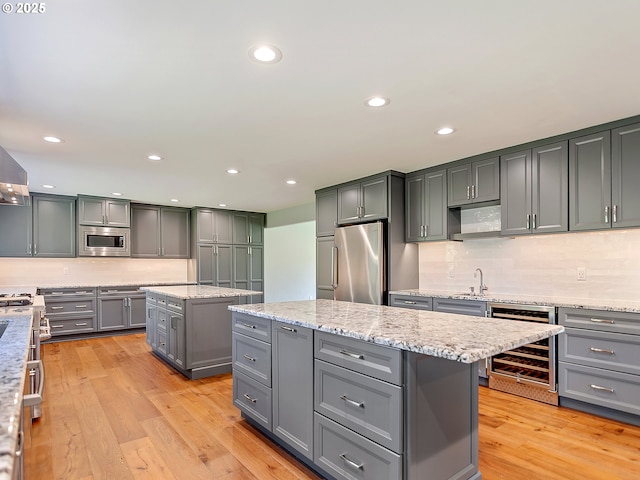 kitchen featuring beverage cooler, a center island, stainless steel appliances, gray cabinets, and tasteful backsplash