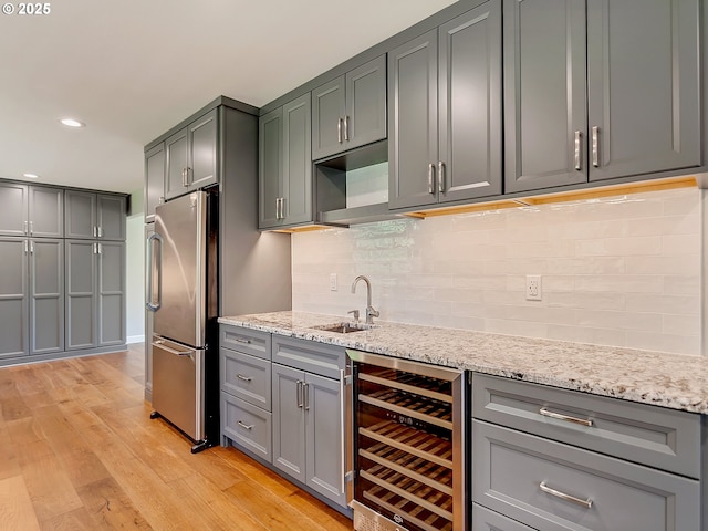 kitchen featuring gray cabinets, light wood-style flooring, a sink, and wine cooler