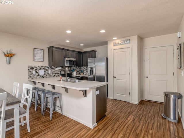 13012 NE 115th St, Vancouver, WA 98682 - kitchen featuring appliances with stainless steel finishes, a peninsula, wood finished floors, a kitchen bar, and light countertops