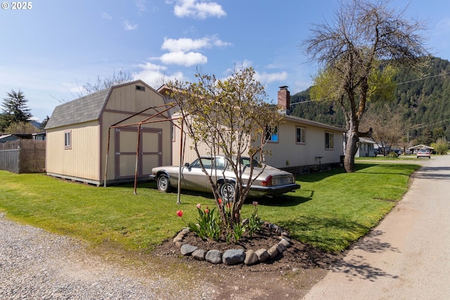 view of front of property featuring a storage shed and a front lawn