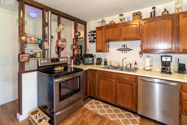 kitchen featuring appliances with stainless steel finishes, sink, and light hardwood / wood-style flooring