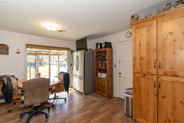 interior space featuring hardwood / wood-style flooring, stainless steel fridge, and light brown cabinetry