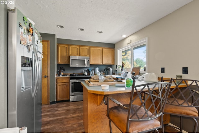 2012 SE Evans Ave, Troutdale, OR 97060 - kitchen with appliances with stainless steel finishes, dark wood-style floors, a textured ceiling, light countertops, and brown cabinets