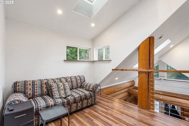 living area with a skylight, high vaulted ceiling, recessed lighting, and wood finished floors