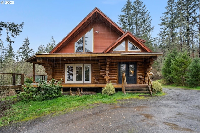 rear view of property featuring french doors, a deck, log siding, and a porch