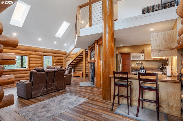 cinema featuring a skylight, log walls, high vaulted ceiling, and wood finished floors