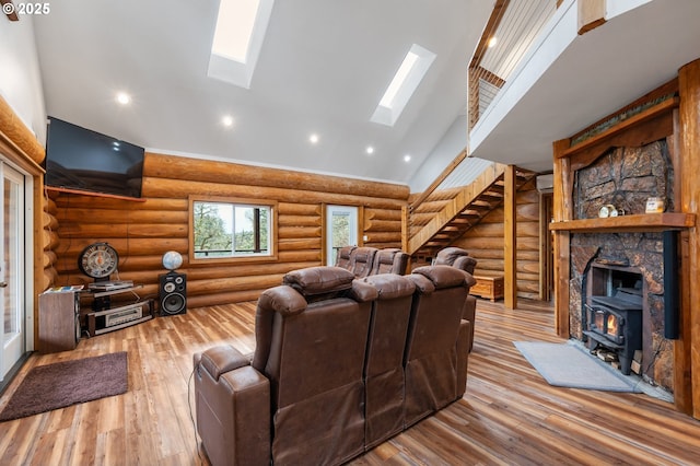 living room featuring a skylight, a wood stove, stairway, high vaulted ceiling, and wood-type flooring