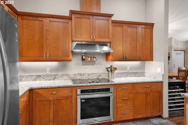 5030 Heceta Park Way, Florence, OR 97439 - kitchen featuring stainless steel appliances, extractor fan, brown cabinetry, light stone countertops, and wine cooler