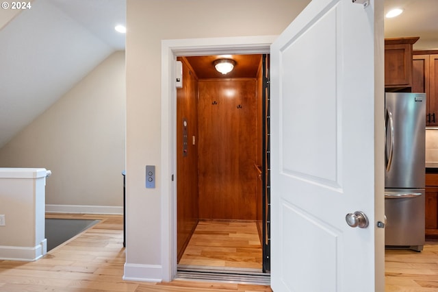 interior space featuring light hardwood / wood-style floors, elevator, and lofted ceiling