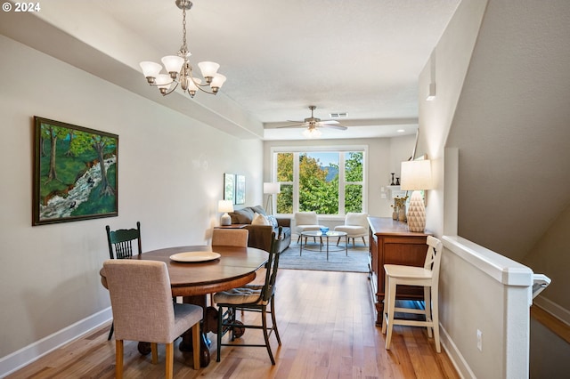 dining space with ceiling fan with notable chandelier and hardwood / wood-style floors