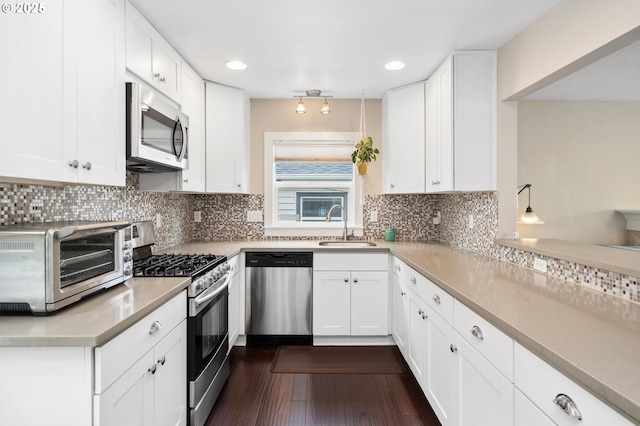 kitchen with recessed lighting, light countertops, a sink, appliances with stainless steel finishes, and white cabinetry