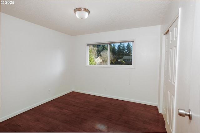 unfurnished room featuring dark wood-type flooring and a textured ceiling