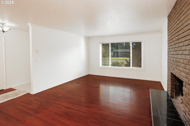 unfurnished living room with dark wood-type flooring, a fireplace, a textured ceiling, and crown molding