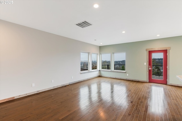 spare room with wood-type flooring, visible vents, and a healthy amount of sunlight