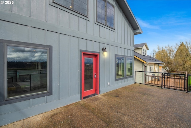 view of exterior entry with board and batten siding and a patio area