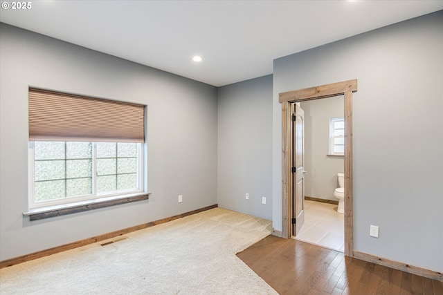 carpeted spare room featuring recessed lighting, visible vents, baseboards, and wood finished floors