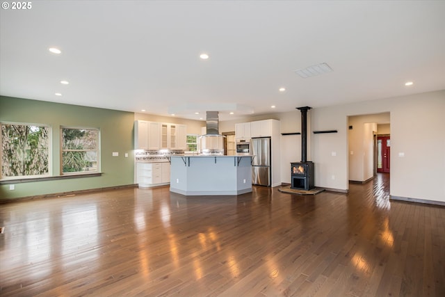 kitchen with a center island, appliances with stainless steel finishes, white cabinets, island range hood, and a kitchen bar