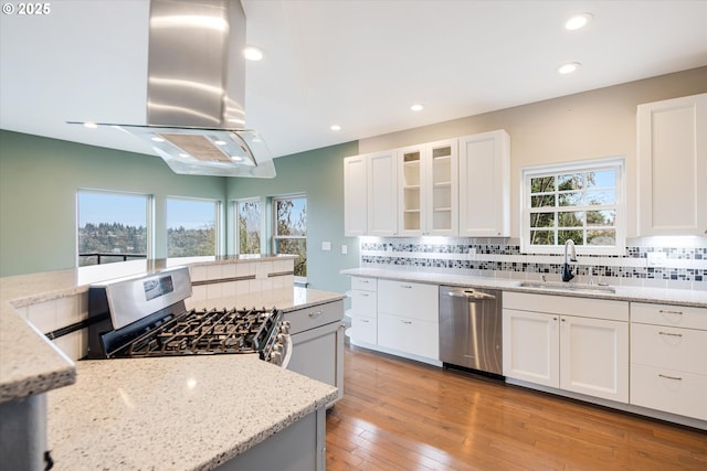 kitchen featuring island exhaust hood, stainless steel appliances, tasteful backsplash, and a sink