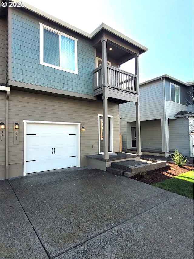 rear view of house featuring a garage, driveway, and a balcony