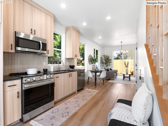 207 NE Going St Unit 3, Portland, OR 97211 - kitchen with appliances with stainless steel finishes, light brown cabinetry, dark countertops, backsplash, and light wood-style floors