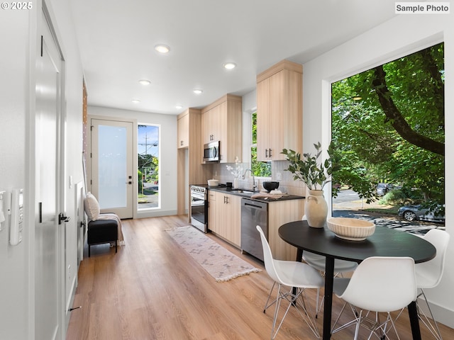 207 NE Going St Unit 3, Portland, OR 97211 - kitchen featuring stainless steel appliances, light brown cabinets, dark countertops, light wood-type flooring, and decorative backsplash