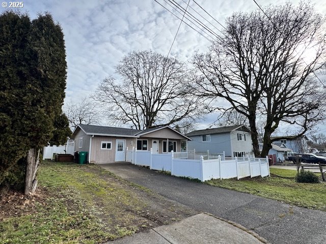 ranch-style home with driveway and a fenced front yard