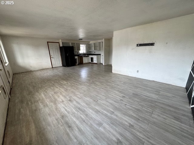 unfurnished living room featuring a textured ceiling and wood finished floors