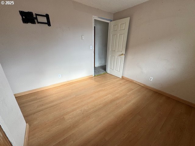 spare room featuring baseboards and wood finished floors