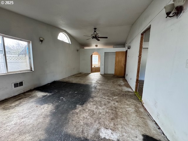 unfurnished living room featuring arched walkways, visible vents, concrete floors, and ceiling fan