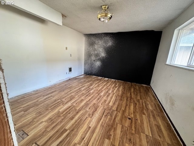 unfurnished room featuring a textured ceiling and wood finished floors