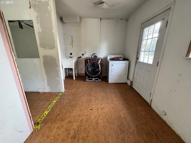 clothes washing area featuring a sink, laundry area, separate washer and dryer, and wood finished floors