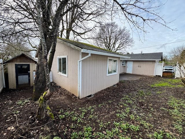 exterior space featuring a storage shed, fence, and an outdoor structure