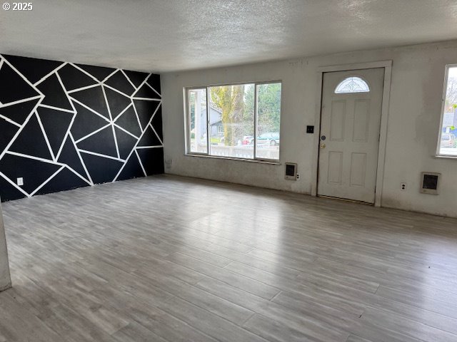 foyer with a textured ceiling, heating unit, and wood finished floors