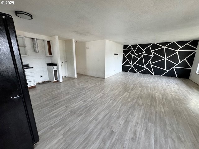 unfurnished living room with a textured ceiling and wood finished floors