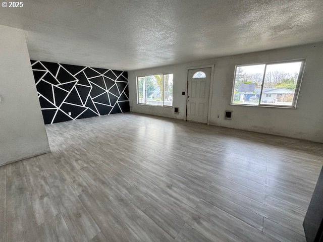 unfurnished living room featuring a textured ceiling and wood finished floors