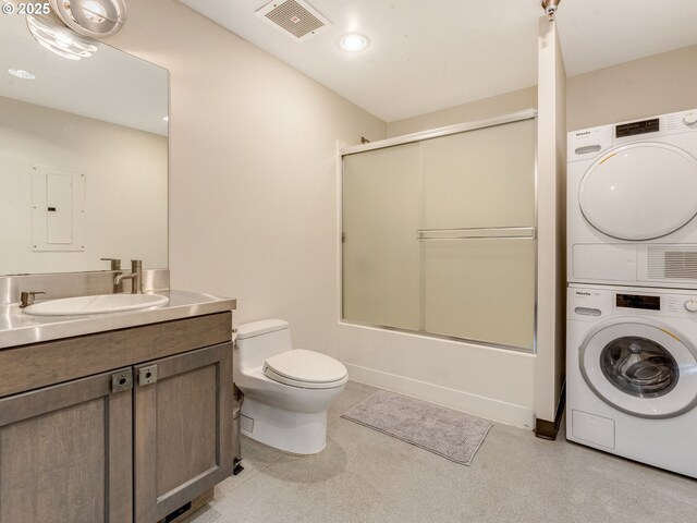 full bathroom featuring shower / bath combination with glass door, stacked washer / dryer, vanity, and toilet