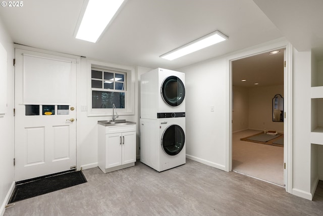 laundry area featuring sink, light hardwood / wood-style floors, cabinets, and stacked washer / dryer